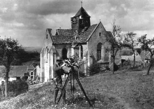 SIGNAL CORPS PHOTOGRAPHER OPERATES A CAMOUFLAGED CAMERA IN FRANCE
