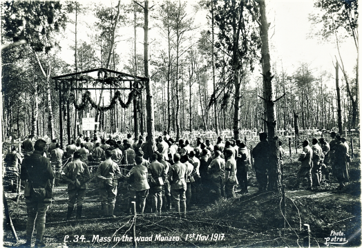Mass in the wood Monaco. 1st Nov. 1917 a large group of soldiers stands in a forest facing a makeshift altar built between the trees barned wire and crosses
